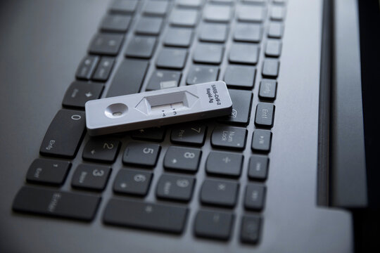 Corona rapid test kit on laptop keyboard at home