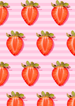 Pattern of rows of fresh halved strawberries lying against pink striped background