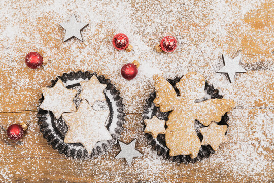 Christmas ornaments and fresh homemade cookies lying on wooden surface