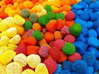 Bright and juicy gummy candies.  The chocolates are poured in a large pile of different colors and sizes.