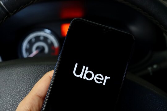 Bahia, Brazil - April 30, 2021: Person in a car holding smartphone with Uber app displayed.