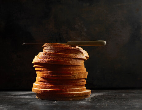 Studio shot of kitchen knife lying on top of stack of fresh bread slices