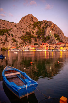 Croatia,&nbsp;Split-Dalmatia&nbsp;County, Omis, Rowboat moored in front of coastal town&nbsp;at dusk