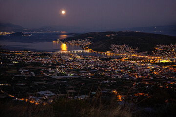 Reflection of full moon in water by town at night, Trogir, Croatia