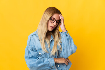 Young blonde woman isolated on yellow background with headache