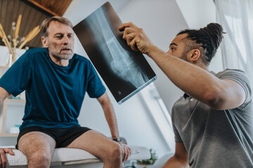 Physiotherapist discussing x-ray image of knee with male patient