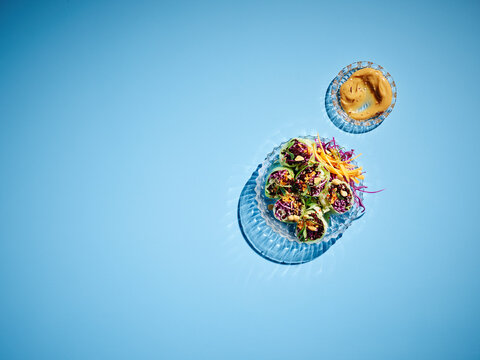 Studio shot of dipping bowl with peanut butter and larger bowl of cabbage rolls with black rice, carrot and sesame seeds