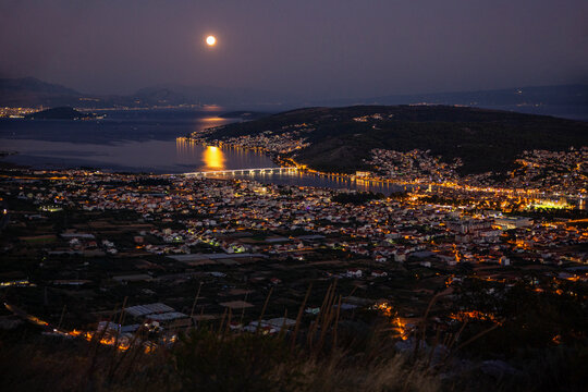 Reflection of full moon in water by town at night, Trogir, Croatia