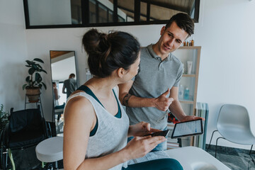 Male physiotherapist with digital tablet showing thumbs up to female patient in medical practice