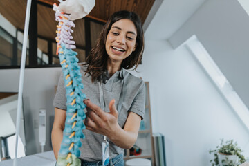 Smiling female trainer explaining spine model in classroom