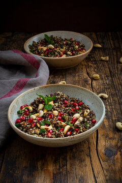 Two bowls of vegan quinoa salad with cashews, pomegranate seeds and mint