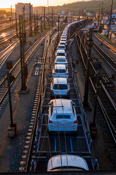 Germany, Bavaria, Wurzburg, Row od cars transported along city railroad tracks at sunset