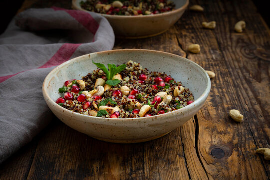 Bowl of vegan quinoa salad with cashews, pomegranate seeds and mint