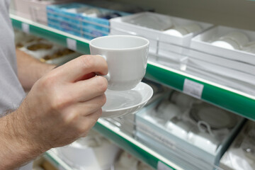 The man has white dishes in his hands. Close-up of a plate and saucer