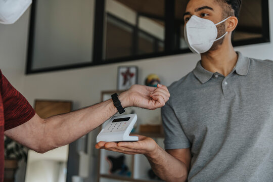 Physiotherapist holding credit card reader while patient using smart watch in medical practice