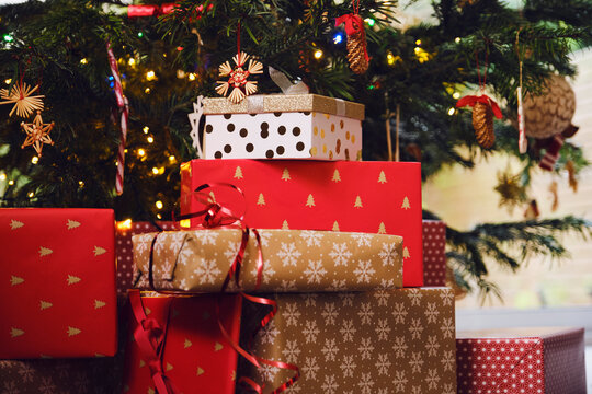 Stack of gifts in front of Christmas tree at home