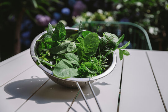 Mixed herbs in colander at table