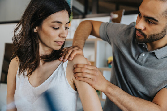 Physiotherapist working on shoulder of female patient in practice