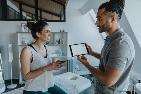 Physiotherapist discussing with female patient over digital tablet in medical practice - Powered by Adobe