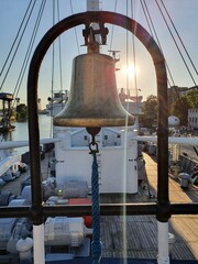 Bell aboard the ship. Bright rays of the sun shine on the deck.