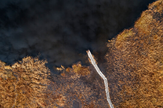 Drone view of jetty on brown grassy shore of Lej da Staz lake in autumn