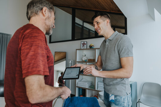 Smiling male physiotherapist discussing over digital contract with patient in practice