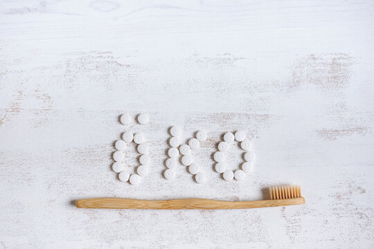 Bamboo material toothbrush with toothpaste pill on textured background