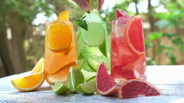 Squeezes fresh lime juice into an ice drink mojito. Mix of three ice refreshing drinks with orange, lime and grapefruit. Summer refreshing drink