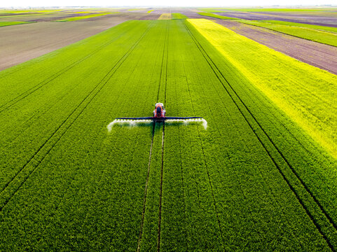 Tractor spraying pesticide on agricultural field