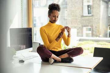 Female professional assembling wooden cube puzzle while sitting on desk in office