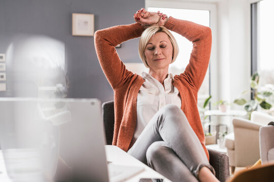 Blond businesswoman relaxing with eyes closed in home office