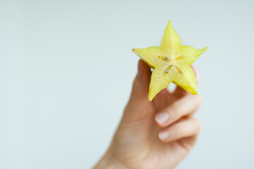 Female hands are holding slice of exotic ripe starfruit or averrhoa carambola. Healthy food, fresh organic star apple fruit