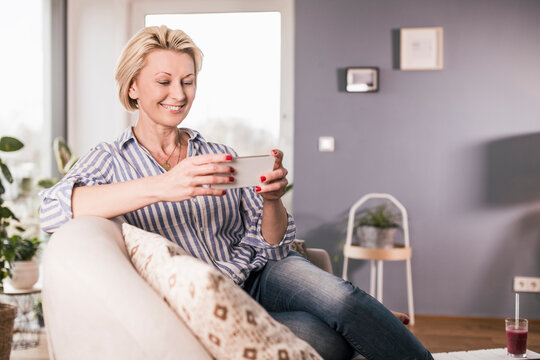 Mature woman watching on smart phone in living room