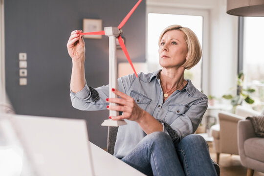 Thoughtful female professional examining wind turbine model at home office