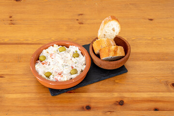 Top of Russian salad with olives with a bowl of bread spread