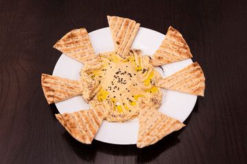 Chickpea hummus appetizers with olive oil and pieces of unleavened bread to dip