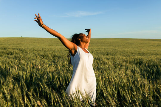 African American female in dress walking on grassy meadow