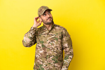 Military man isolated on yellow background thinking an idea
