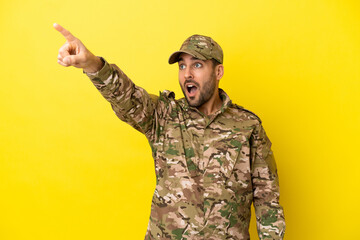 Military man isolated on yellow background pointing away