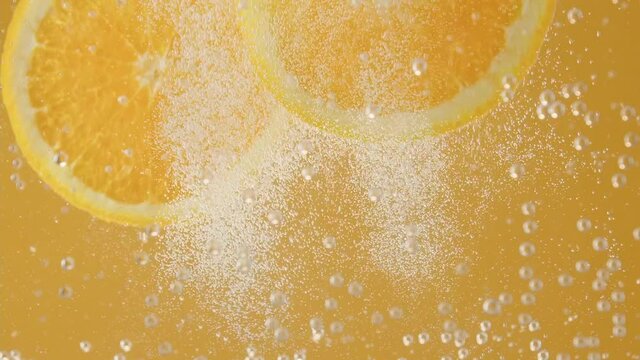 orange slices fall into sparkling water