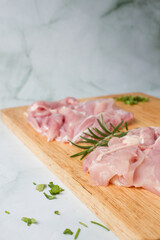Raw chicken breast with herbs over a wood plate, green background