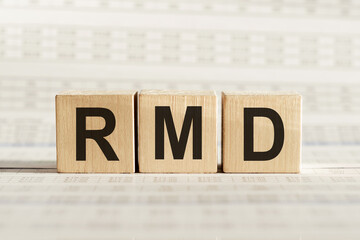 RMD abbreviation - required minimum distributions, on wooden cubes on a light background.