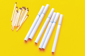 Unhealthy lifestyle concept . Cigarettes and matches at yellow background
