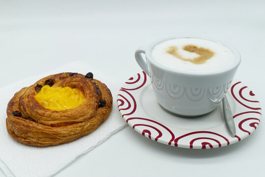 Traditional Italian breakfast, Cappuccino coffee with raisins cream brioche, isolated on white background.