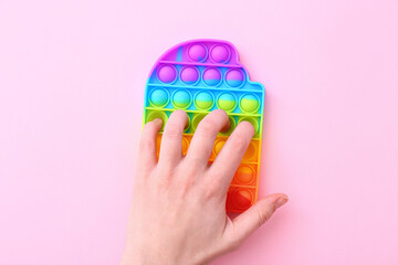 Colorful antistress sensory toy fidget push pop it on pink background, top view