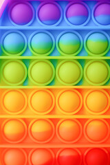 Colorful antistress sensory toy fidget push pop it on pink background, close-up