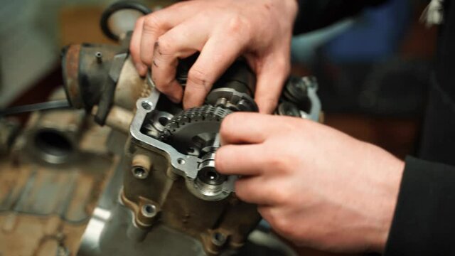 A man installs a star with a chain in the valve block of an ATV engine