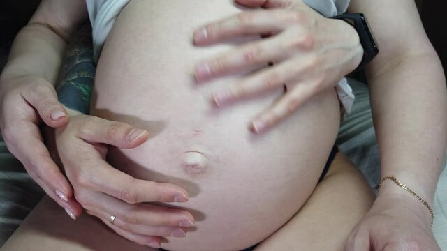 Hands of dad and mom on the pregnant woman's stomach