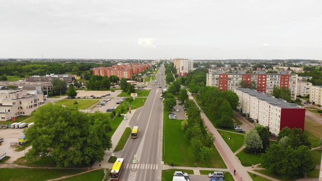 Tilt down view Siauliai city road with yellow buses in Lithuania.Transportation in post soviet union countries