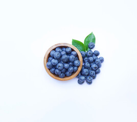 Blueberries on bowl white background. Some berries and green leaves around. Top view. 